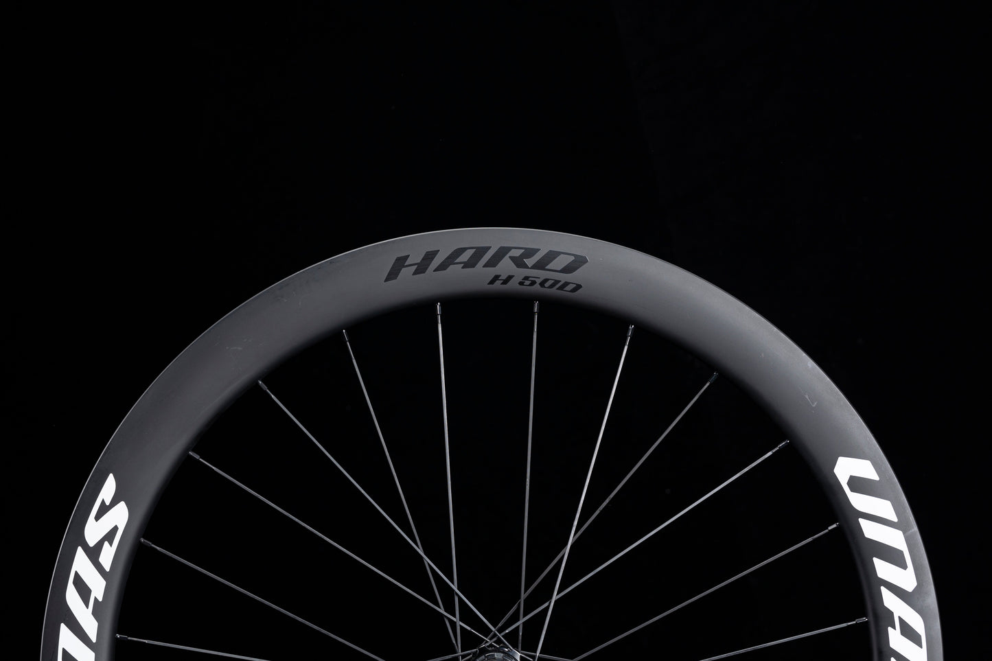 Matte black UNAAS HARD H50D 50mm deep carbon wheelset rim with white decals and silver spokes, showcasing product appearance.