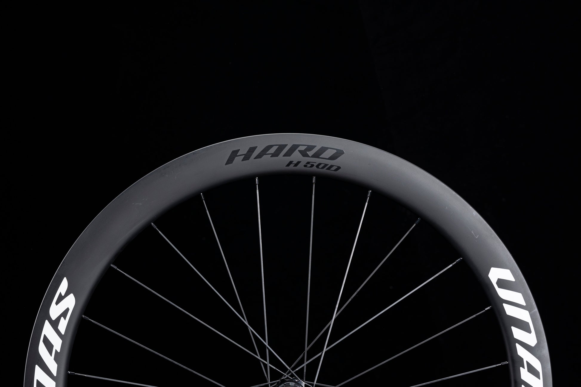 Matte black UNAAS HARD H50D 50mm deep carbon wheelset rim with white decals and silver spokes, showcasing product appearance.