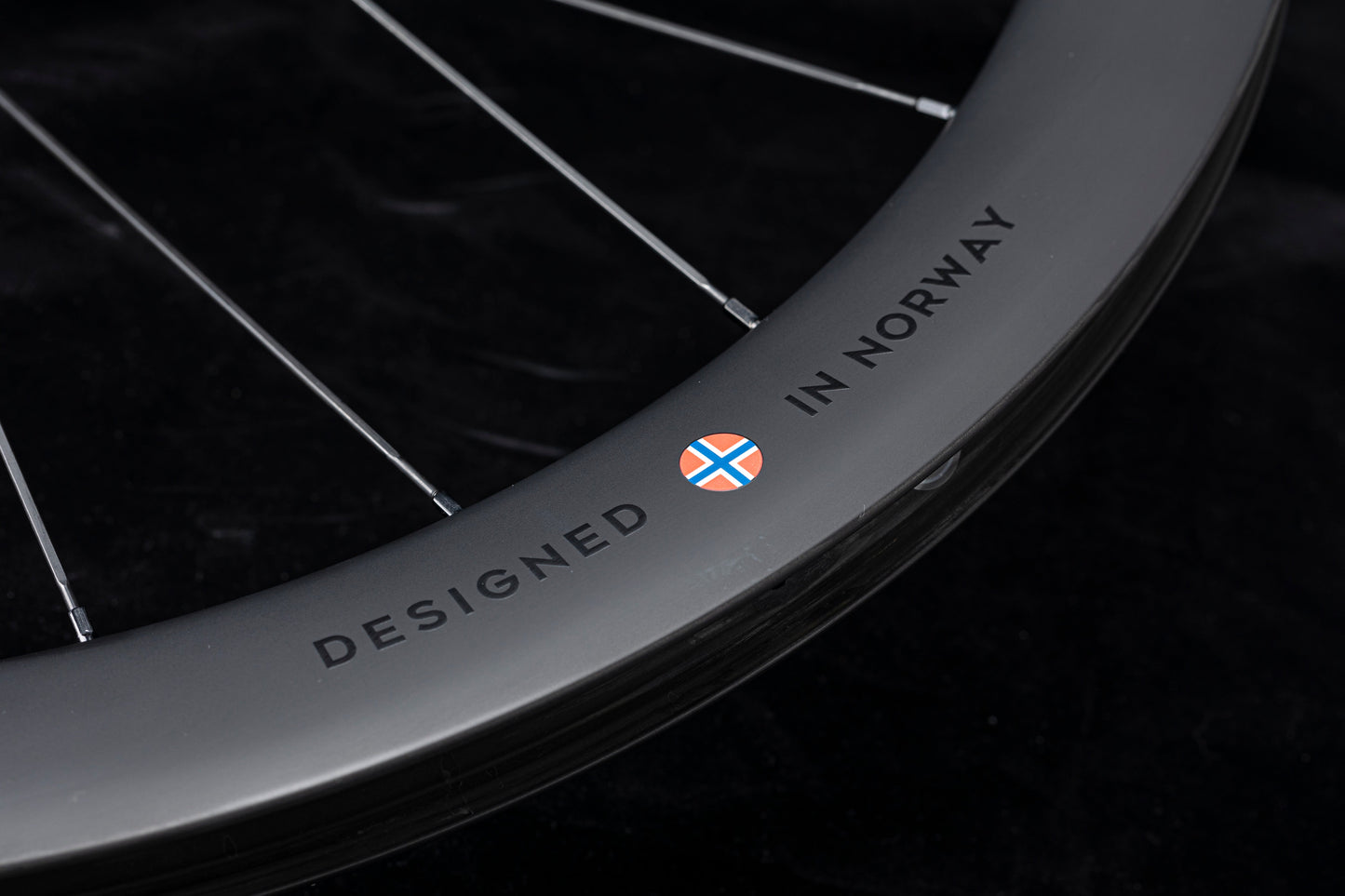 UNAAS HARD H50D 50mm matte black carbon wheelset rim with silver spokes and "DESIGNED IN NORWAY" decal.