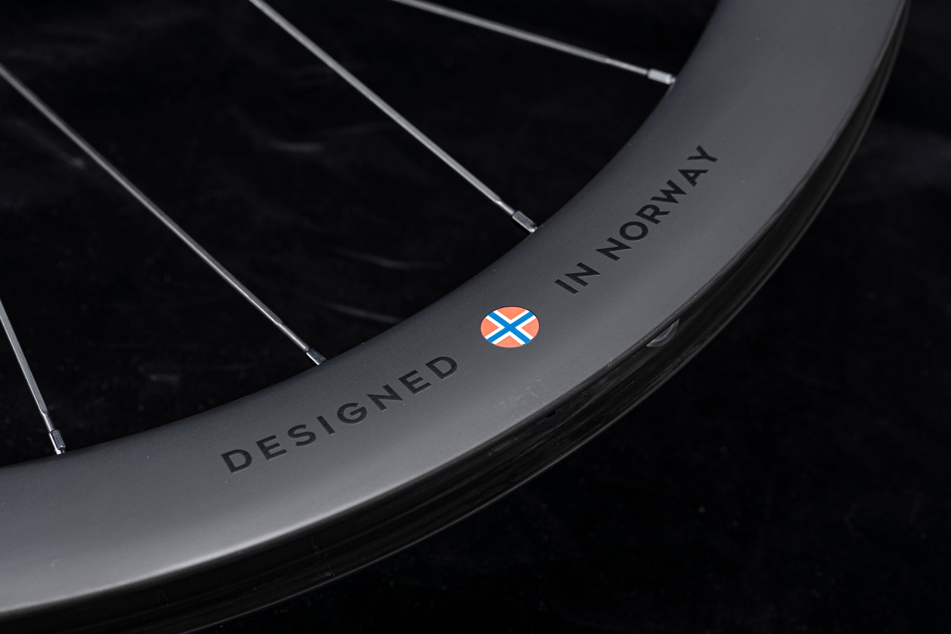 UNAAS HARD H50D 50mm matte black carbon wheelset rim with silver spokes and "DESIGNED IN NORWAY" decal.
